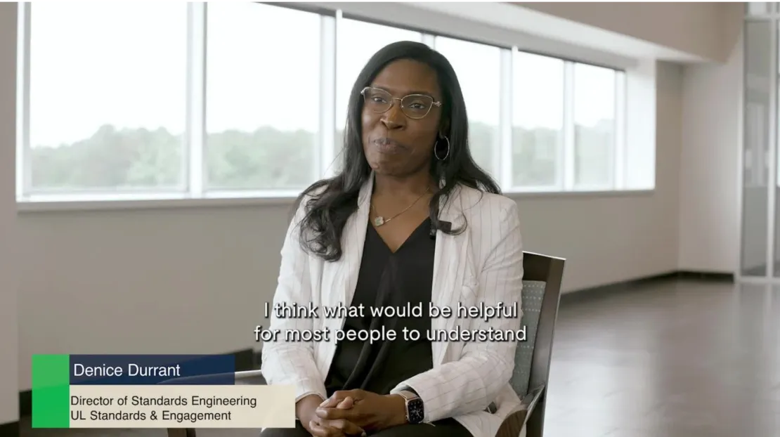 A woman with long black hair and glasses is seated and speaking in an office environment. The subtitle reads, "I think what would be helpful for most people to understand." The on-screen text identifies her as Denice Durrant, Director of Standards Engineering, UL Standards & Engagement.